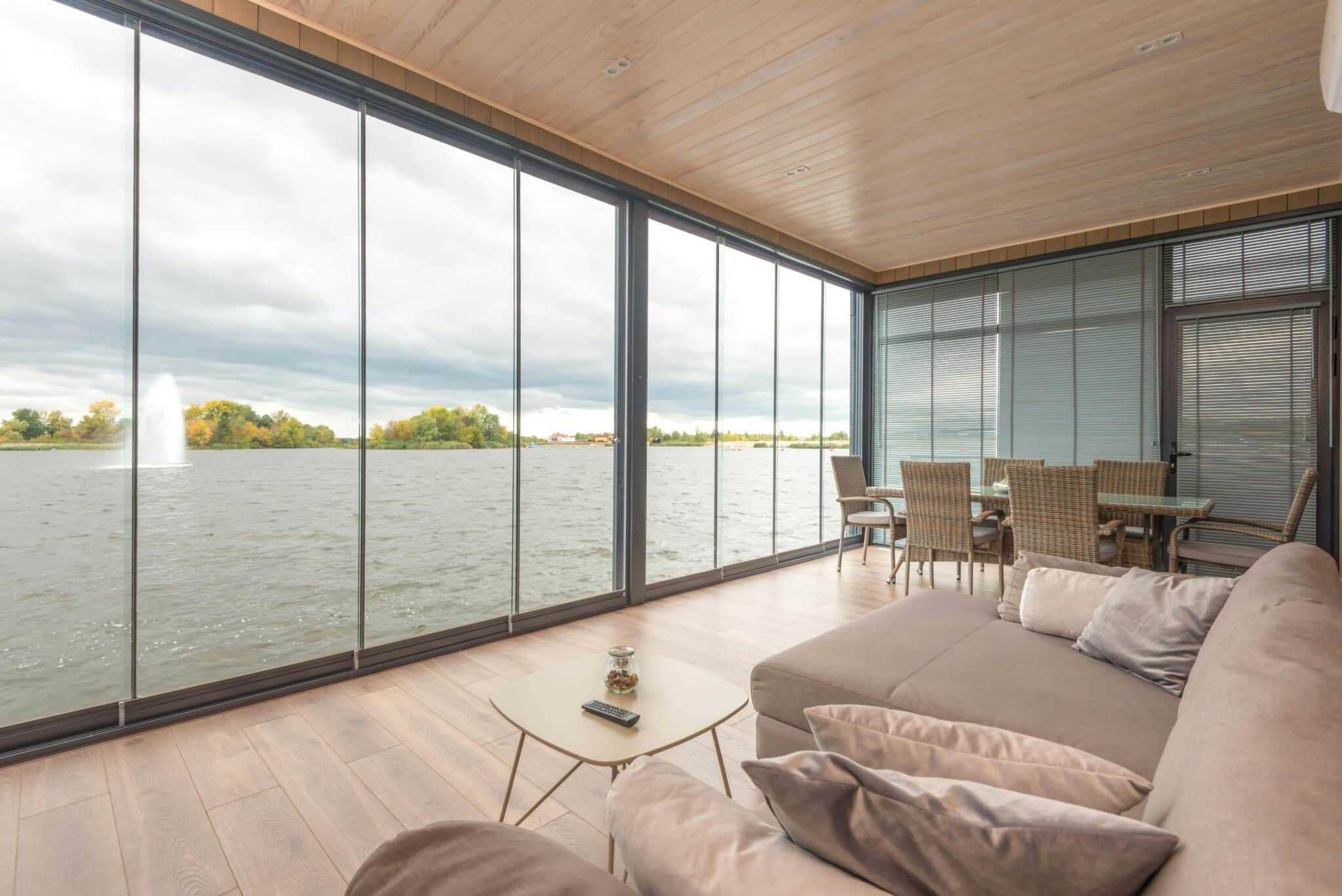 Stunning lakeside living room with floor-to-ceiling glass windows, modern furniture, and scenic water views.